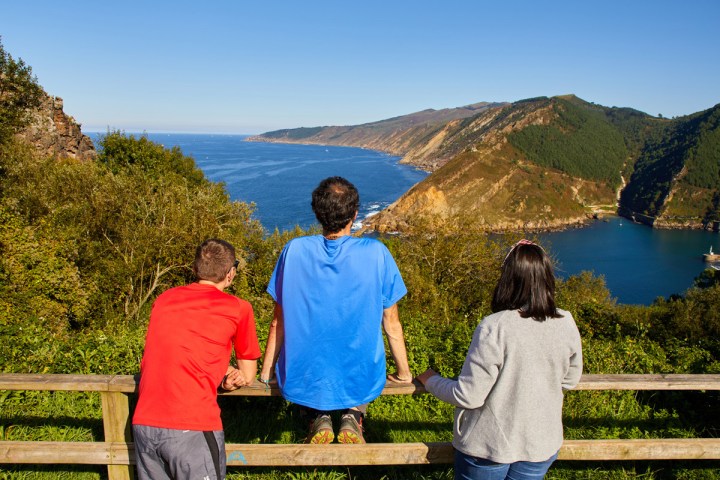 a group of people sitting on a bench in front of a mountain