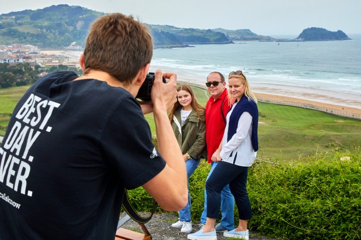 a person standing next to a body of water talking on a cell phone